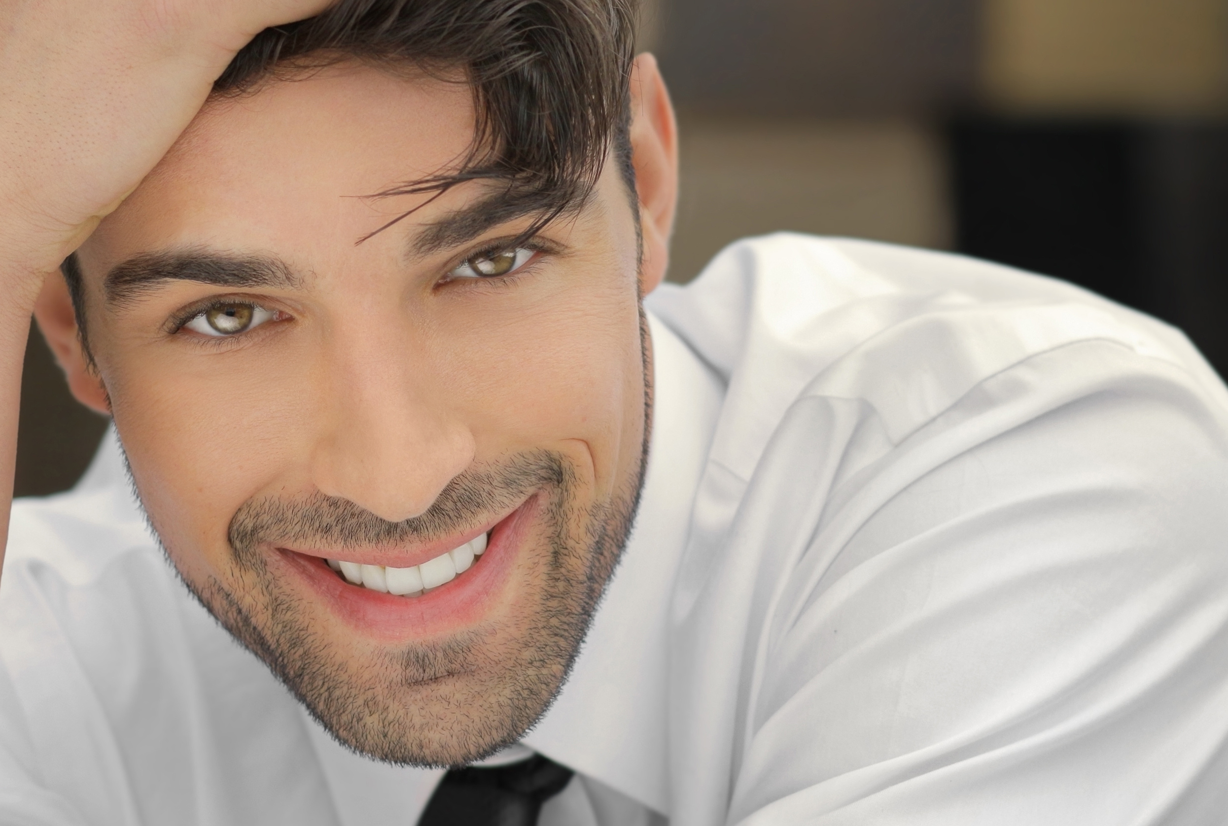 Handsome young man leaning on his hand with nice big real smile